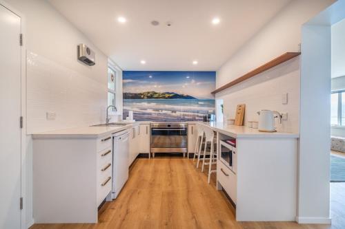 a kitchen with white cabinets and a painting on the wall at Luxury Beachfront Apartment - Private Lower Suite in Wellington
