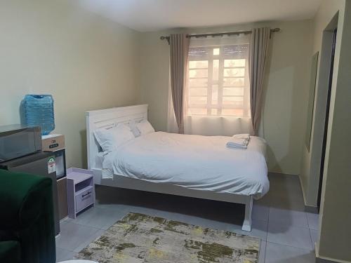 a small bedroom with a bed and a window at Legatus Cozy Studios Ngong in Ngong