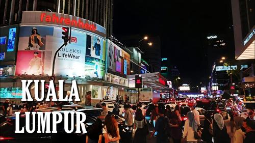a crowd of people on a busy city street at night at Agile TRX Luxury Condo in Bukit Bintang in Kuala Lumpur