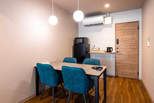 a kitchen with a table and blue chairs in a room at Amp Flat Arc Bliss 2B in Chikushino