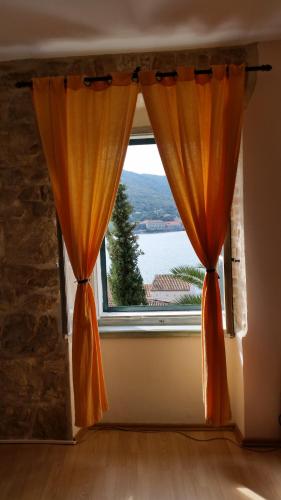 a window with an orange curtain in a room at Buena Vis-ta Apartments with the Sea View in Vis
