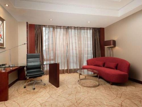 a living room with a red couch and a desk at Wuhan Soluxe Hotel in Wuhan
