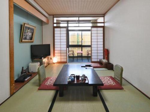 a living room with a table and chairs and a television at Futami Onsen Hotel Seikai in Ise
