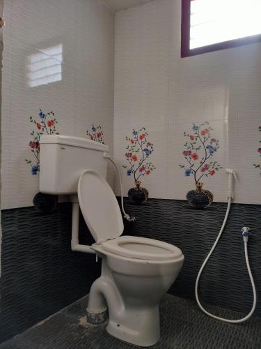 a bathroom with a toilet and flowers on the wall at Isakki Cottage in Thiruchendur