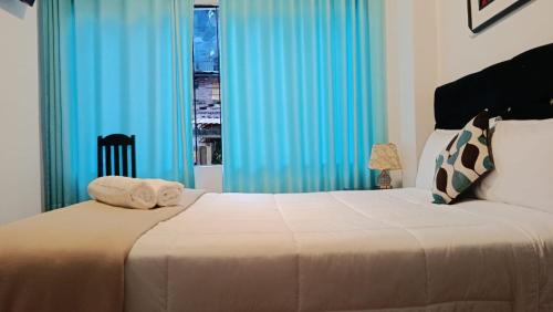 a bedroom with a bed with blue curtains and a window at Inkary Hotel Machupicchu in Machu Picchu