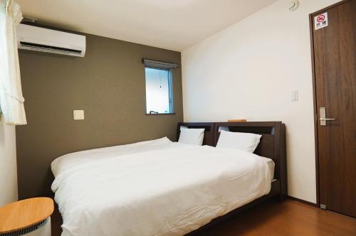 a bedroom with a large white bed and a window at 一組貸切の戸建民泊旅館 熊本熊猫基地 新町 Kumamoto Panda Base Shinmachi in Kumamoto
