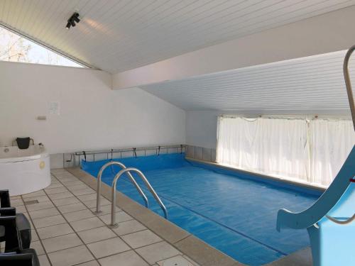 a large indoor swimming pool with a large blue pool at 4 star holiday home in Væggerløse in Bøtø By