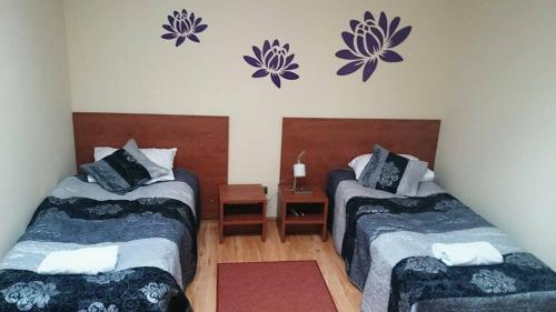 シェドルツェにあるHotel Restauracja Księżycowaの紫色の花が壁に飾られた客室内のベッド2台