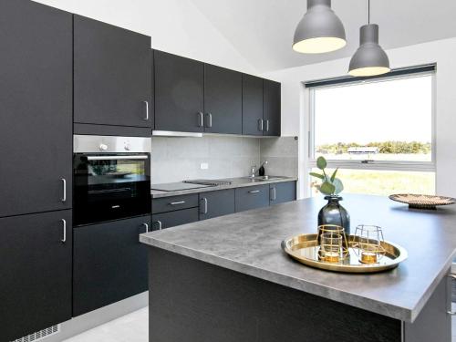 a kitchen with black cabinets and a large window at Modern Retreat with Spa - By Traum Ferienwohnungen in Løkken