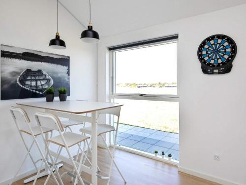 a dining room with a table and chairs and a clock at Modern Retreat with Spa - By Traum Ferienwohnungen in Løkken