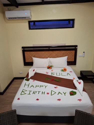 a bed with a happy eighth day written on it at Bulabard Villa in Nayawa