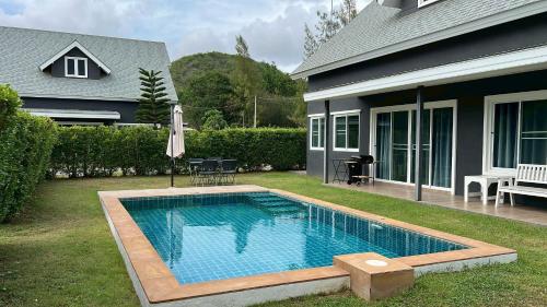 a swimming pool in a yard next to a house at The Barn Hua Hin in Khao Tao