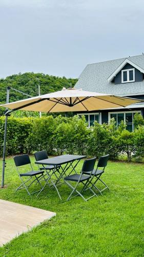 a table and chairs under an umbrella in the grass at The Barn Hua Hin in Khao Tao