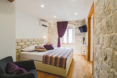 een slaapkamer met een bed en een stenen muur bij Sir George Luxury Suites in Split