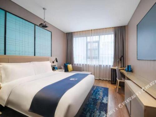 a hotel room with a large bed and a screen at Echarm Hotel Changsha Wuyi Square Xiangya Affiliated 1st Provincial Maternity and Child in Changsha