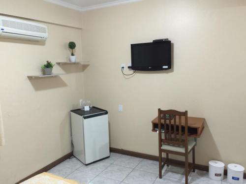 a room with a refrigerator and a chair and a table at Fares Turis Hotel in Uruguaiana
