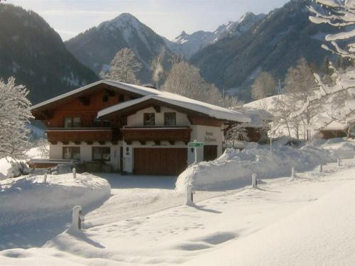 a house covered in snow with mountains in the background at Sauna Apartment in Schladming in Schladming