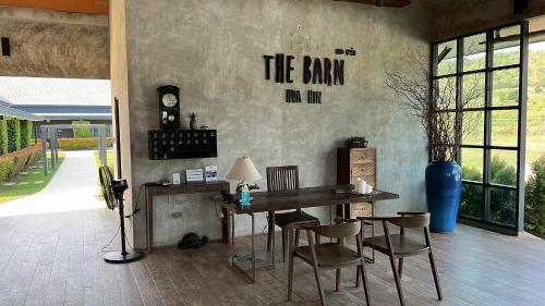 a dining room with a table and chairs and a clock on the wall at The Barn Hua Hin in Khao Tao