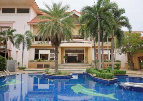 a swimming pool with palm trees in front of a building at Eastern Grand Palace in Pattaya South