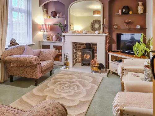 a living room with a fireplace and a television at Lavender Cottage in Louth