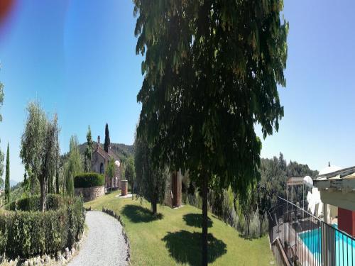 a garden with trees and a walkway next to a house at Montalceto Tuscan Nest in Serre di Rapolano