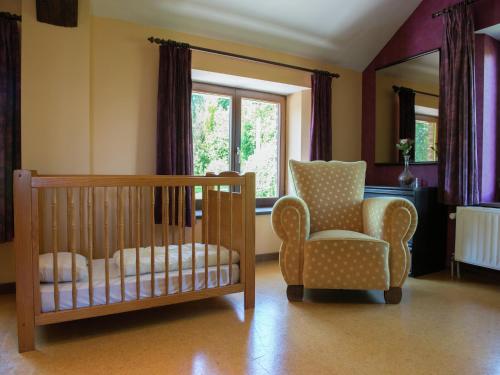 a room with a crib and a chair and a window at Desnié Farmhouse with Pool in Desnié