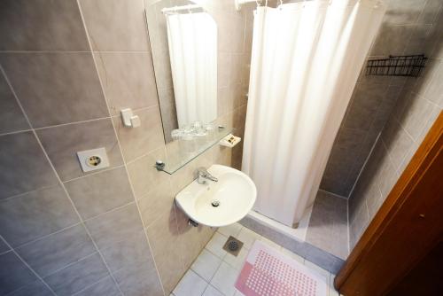 a bathroom with a sink and a shower with a shower curtain at Guest House Bakhus in Žerjavka