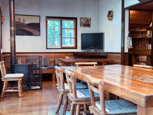 a dining room with a table and chairs and a television at Ringo Lodge Hakuba in Hakuba