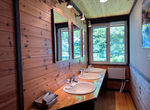 a bathroom with three sinks and two mirrors at Ringo Lodge Hakuba in Hakuba