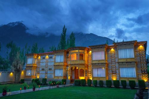 a large building at night with mountains in the background at Khar Hotel in Skardu