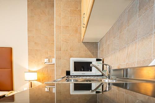 a kitchen with a sink and a microwave at Kingsgate Hotel Doha by Millennium Hotels in Doha
