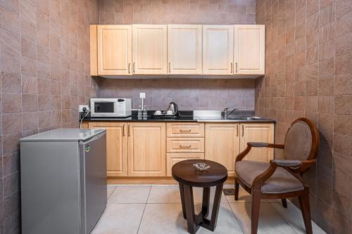a kitchen with a refrigerator and a chair and a table at Kingsgate Hotel Doha by Millennium Hotels in Doha