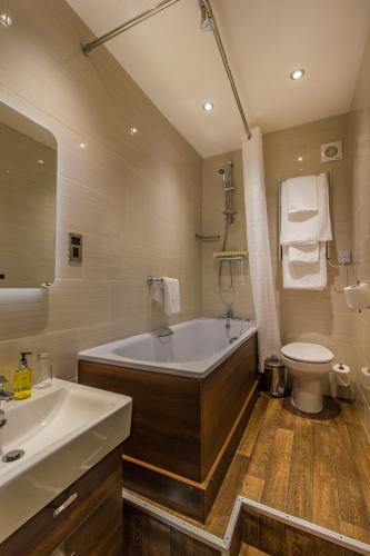 a bathroom with a tub and a toilet and a sink at The Kings Head Hotel, Richmond, North Yorkshire - The Coaching Inn Group in Richmond