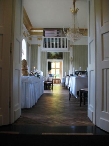 a dining room with white tables and chairs and a chandelier at Pałac Bażantarnia in Pszczyna
