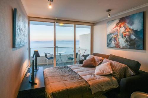 a bedroom with a bed and a view of the ocean at Apartamento en Costa Horizonte in Concón