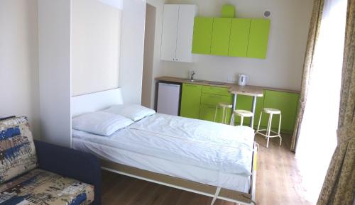 a bedroom with a bed and a kitchen with green cabinets at Maironio apartamentas in Palanga