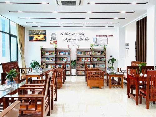 a restaurant with wooden tables and chairs and bookshelves at HOMESTAY Hoàng GIa in Ấp Ông Tú