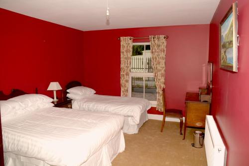 a red room with two beds and a window at The Gate Lodge Cannaway House in Macroom