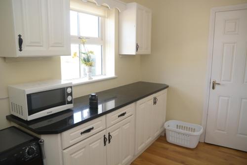 a kitchen with a counter with a microwave and a window at The Gate Lodge Cannaway House in Macroom