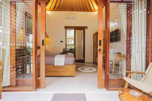 Un dormitorio con una cama y una puerta de cristal. en Nubi Villas Gili Trawangan, en Gili Trawangan
