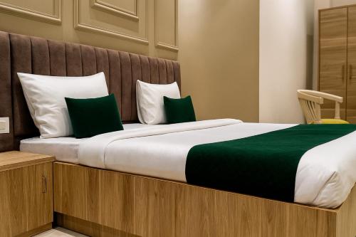 a bedroom with a bed with green and white pillows at Hotel Citi Continental in New Delhi