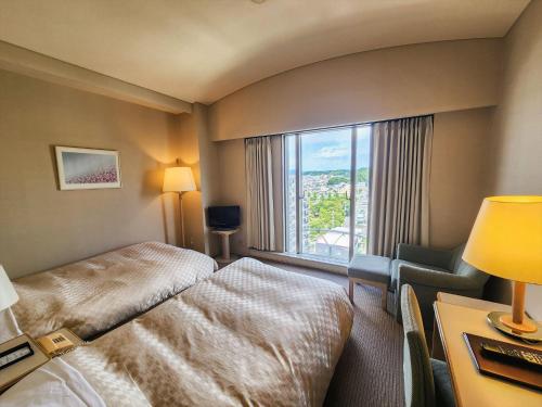 a hotel room with a bed and a window at Palace Hotel Kakegawa in Kakegawa