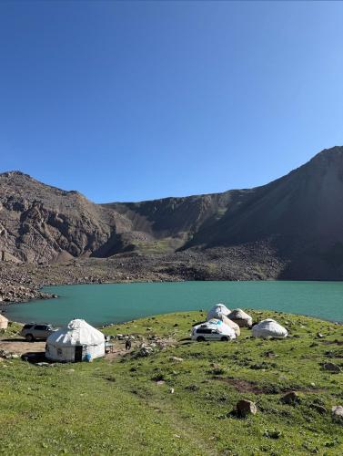 a group of tents on a hill next to a lake at Bagysh Hotel in Kochkor