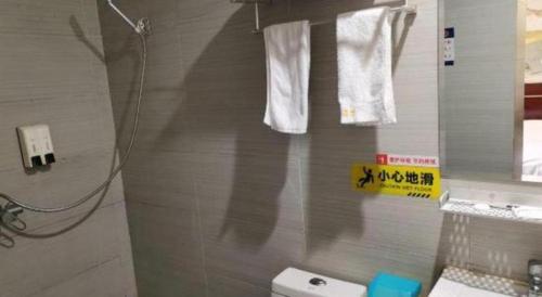 a bathroom with white towels hanging on a wall at Shell Hotel Shanghai Baoshan Meilanhu Luosheng Road in Shanghai
