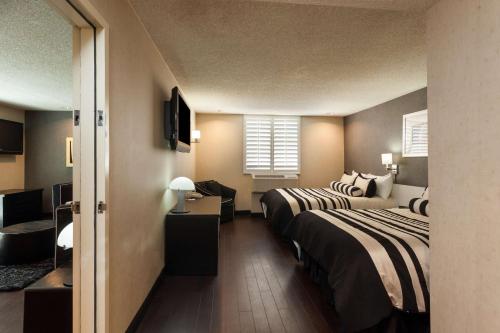 a hotel room with two beds and a desk at Ramada Plaza by Wyndham West Hollywood Hotel & Suites in Los Angeles