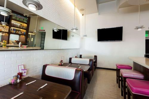 a restaurant with tables and chairs and a tv on the wall at Ramada Plaza by Wyndham West Hollywood Hotel & Suites in Los Angeles