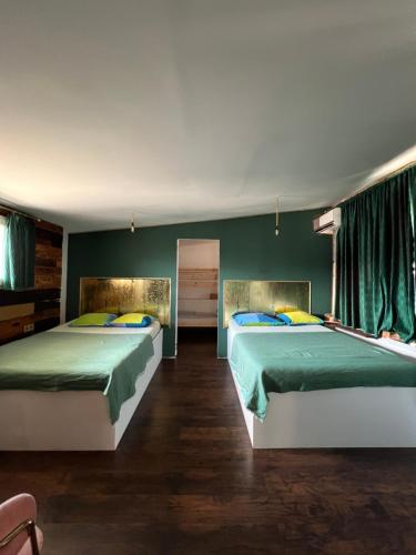 two beds in a room with green walls and wooden floors at Old Town Penthouse 16 guests in Bucharest