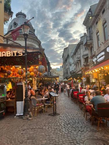 a crowd of people sitting at tables in a street at Old Town Penthouse 16 guests in Bucharest