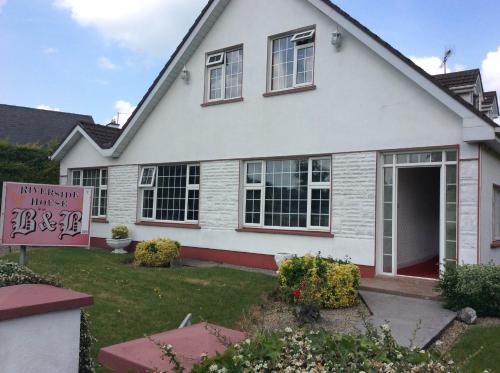 a white house with a sign in front of it at Riverside House in Roscommon