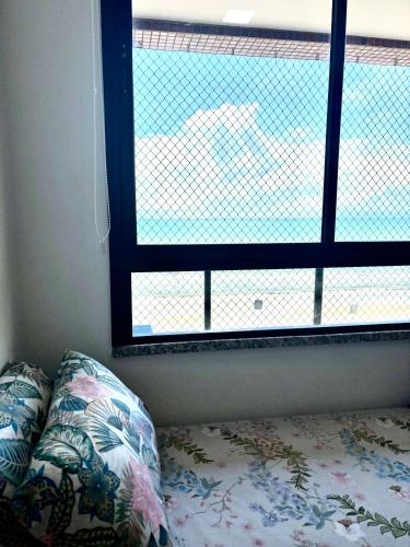a bed with a pillow in front of a window at Frente a Mar na Praia dos Milionários in Ilhéus